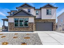 Beautiful two-story home featuring stone accents, gray siding, a two-car garage, and a concrete driveway at 5698 Farrier Pt, Castle Rock, CO 80104
