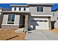 Charming two-story home featuring stone accents, a two-car garage, and a well-manicured lawn at 9121 Telluride Ct, Commerce City, CO 80022