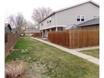A spacious backyard features a lush green lawn and a tall wood fence, perfect for outdoor entertaining at 1015 Alta St, Longmont, CO 80501