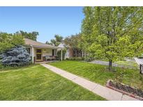 Charming home featuring a well-manicured lawn and mature trees under a clear blue sky at 1292 Kearney St, Denver, CO 80220