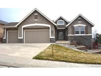 Inviting two-story home with stone accents, a well-manicured lawn, and a two-car garage, perfect for families at 461 Saber Creek Dr, Monument, CO 80132