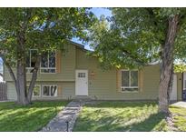 Charming home with inviting entryway, manicured lawn, stone walkway, mature trees, and neutral toned siding at 18932 W 60Th Dr, Golden, CO 80403