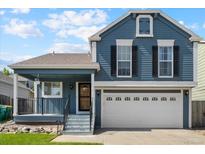 Charming two-story home with blue siding, white garage door, and manicured lawn at 9816 Garwood St, Littleton, CO 80125