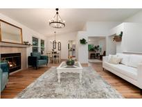 Bright living room featuring hardwood floors, a fireplace, modern furnishings, and an open floor plan at 8543 Redstone St, Highlands Ranch, CO 80126