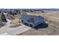 An aerial view of a blue two-story house with a two-car garage and concrete driveway in a suburban setting at 14701 Yosemite St, Brighton, CO 80602