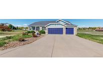 Charming two-story home featuring a blue garage door, landscaped front yard, and inviting front porch at 14701 Yosemite St, Brighton, CO 80602