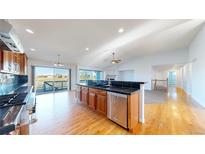 Bright kitchen with hardwood floors, black countertops, stainless steel appliances and sliding glass door to the backyard at 14701 Yosemite St, Brighton, CO 80602