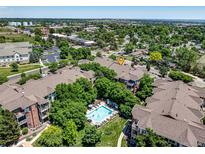 A bird's eye view of the condo complex with a pool, lush green landscaping, and surrounding suburban neighborhood at 2428 W 82Nd Pl # 1D, Westminster, CO 80031