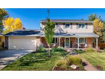 Charming two-story home featuring a brick facade, covered porch, and meticulously maintained lawn and landscaping at 5915 S Race St, Greenwood Village, CO 80121