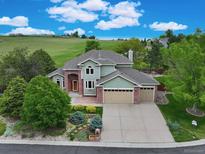 Inviting home with lush landscaping, a brick driveway, and an attached three-car garage offers curb appeal at 8286 W 108Th Pl, Broomfield, CO 80021