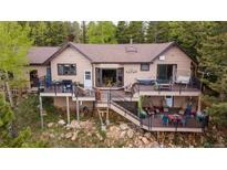 Charming home featuring a spacious deck with outdoor seating, perfect for enjoying the surrounding natural beauty at 11094 Thomas Dr, Conifer, CO 80433