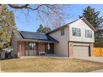 Charming home with a well-maintained lawn, solar panels, and a welcoming front porch and brick facade at 18107 E Belleview Ln, Centennial, CO 80015