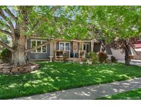 Charming home with a well-maintained lawn, mature trees, and a cozy front porch at 8427 Chase Dr, Arvada, CO 80003