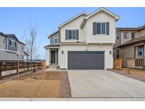 Two-story home featuring white siding, a gray garage door, and a well-manicured lawn at 9257 Truckee Ct, Commerce City, CO 80022