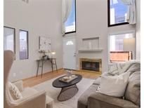 Bright living room with a fireplace, high ceilings, large windows, and modern decor at 1050 S Monaco Pkwy # 106, Denver, CO 80224