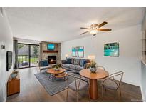 Inviting living room features a stone fireplace, hardwood floors and access to a balcony with outdoor views at 401 S Kalispell Way # 206, Aurora, CO 80017
