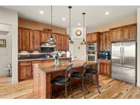 Modern kitchen with a large central island, wood cabinets, stainless steel appliances, and stylish pendant lighting at 2714 Calmante Pl, Superior, CO 80027