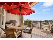 Outdoor dining area on a wood deck, featuring a grill, table and chairs, and scenic views overlooking a pond at 2714 Calmante Pl, Superior, CO 80027
