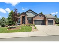 Charming brick home featuring a well-manicured lawn and a three-car garage at 7472 Iridium Way, Castle Rock, CO 80108