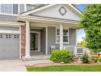 Inviting front porch featuring classic columns, stylish door, and charming landscaping at 16120 E 119Th Ave, Commerce City, CO 80022