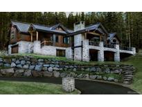Stunning exterior elevation of luxury home with stone accents, wood trim, and lush, mature landscaping at 45 Kerrigan Ct, Breckenridge, CO 80424