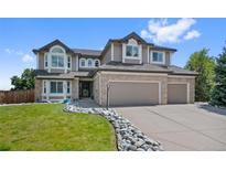 Charming two-story home featuring a well-manicured lawn, rock-lined walkway, and a spacious three-car garage at 7056 S Owens St, Littleton, CO 80127
