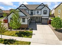 Stunning two-story home featuring white siding, black trim, stone accents, and a well-manicured lawn at 14920 Munich Ave, Parker, CO 80134