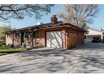 Brick home exterior featuring a garage, driveway, and manicured lawn, creating a welcoming curb appeal at 1475 S Urban Way, Lakewood, CO 80228