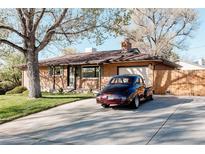 Charming brick home with a well-maintained front yard, mature tree, and a classic car parked in the driveway at 1475 S Urban Way, Lakewood, CO 80228