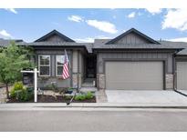 Charming home featuring a two-car garage, stone accents, beautiful landscaping and an American flag at 11823 Barrentine Loop, Parker, CO 80138