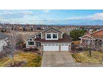 Inviting two-story home showcasing a well-manicured front yard and three-car garage with mountain view in the distance at 22630 E Ida Cir, Aurora, CO 80015