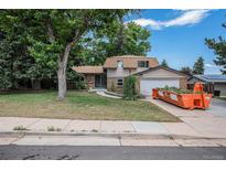 Traditional two-story home featuring a lush lawn, mature trees, and a charming blend of stone and siding exterior at 8727 E Girard Ave, Denver, CO 80231