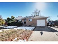 Charming brick home with a driveway, garage, and a yard dusted with snow at 260 E 111Th Pl, Northglenn, CO 80233