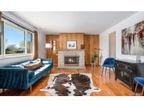 Bright living room featuring hardwood floors, a stone fireplace, and large windows at 8209 Benton Way, Arvada, CO 80003