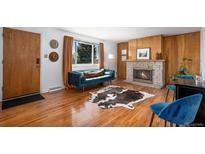 Inviting living room featuring a cozy fireplace, hardwood floors, and a comfortable blue velvet sofa at 8209 Benton Way, Arvada, CO 80003