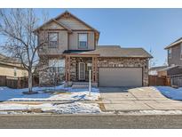 Two-story house with stone accents and attached garage, snow-covered front yard at 164 Bristlecone St, Brighton, CO 80601