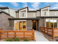 Modern townhome featuring sleek architectural details and inviting entryway with wood railing and sliding glass door at 12331 W 58Th Ct, Arvada, CO 80004