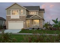 Charming two-story home with stone accents, well-maintained lawn, and attached two-car garage at dusk at 12762 Bend Ct, Firestone, CO 80504