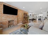 Bright living area featuring exposed brick wall, fireplace, light hardwood floors and modern furnishings at 3005 California St, Denver, CO 80205