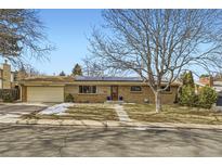 Brick ranch home with solar panels, landscaped yard, and attached garage at 7023 S Buffalo St, Littleton, CO 80120