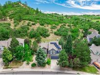 Beautiful aerial view of a blue two story home surrounded by lush greenery and the mountainside in the background at 1412 Pinyon Dr, Castle Rock, CO 80104