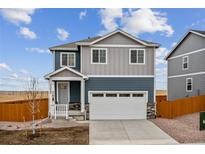 Two-story home with gray siding, white trim, and a two-car garage at 889 Crest St, Lochbuie, CO 80603