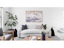 Bright living room features a neutral sofa, modern art, and a tall plant next to a window at 8787 Yukon St, Arvada, CO 80005