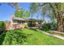 Charming single-story home featuring a brick facade, lush green lawn, and mature trees providing shade at 4781 S Grant St, Englewood, CO 80113