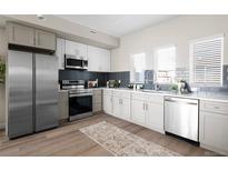 Modern kitchen featuring stainless steel appliances, subway tile backsplash, and hardwood floors at 2620 S Delaware St # 3, Denver, CO 80223