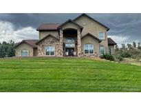 Stunning two-story home featuring a beautiful stone entrance and a lush green front lawn at 4619 Mohawk Dr, Larkspur, CO 80118