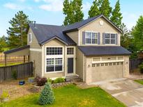 Charming two-story home featuring a spacious front yard, attached garage, and mature trees at 9898 Tourmaline Ct, Parker, CO 80134