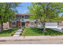 Charming two-story home with mature trees, a manicured lawn, and a welcoming front entrance with double doors at 7359 S Jay St, Littleton, CO 80128