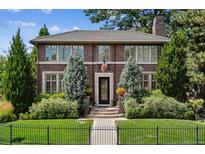 Brick two-story house with a classic design, manicured lawn, and black fence at 87 S Ash, Denver, CO 80246