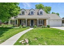 Charming stone-clad home featuring a lush green lawn and well-manicured flowerbeds at 3884 S Niagara Way, Denver, CO 80237